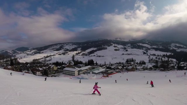 February 2018, La Villa, Italy - Little girl skiing with a beautiful view on a village in mountains