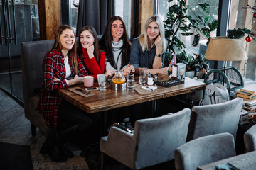 four friends in the cafe look at the camera and laugh