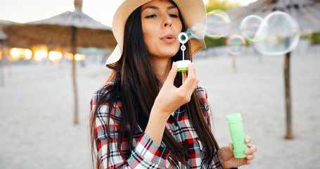 Happy young woman blowing bubbles on the beach