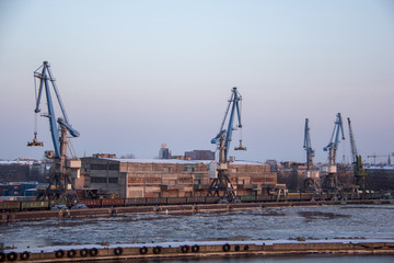 Freight shipping containers and gas oil tanks at the docks. in import export and business logistic. Cargo ship docked at at the port. Cargo cranes by winter evening in the Port Riga, Latvia.