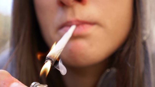 cannabis, marijuana, light drugs: woman smokes a joint,close up