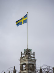 Swedish flag waving in the wind. Skandinavian Sweden flag on grey sky. Stocholm