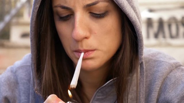 close up portrait of cute young woman lightining her joint-outdoor