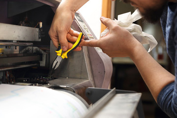 Serwis maszyn. Pracownik serwisu konserwuje  maszynę drukującą