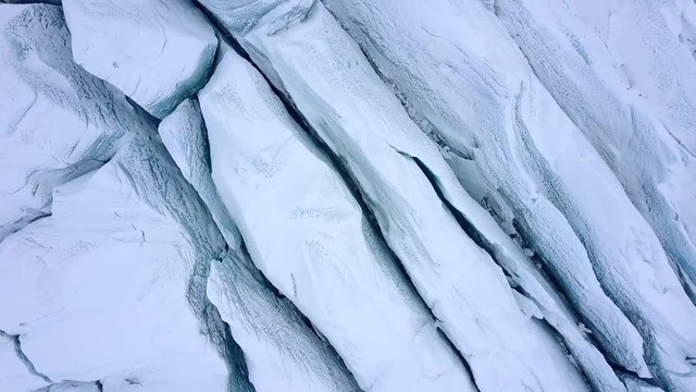 Aerial view of crevasses with visible layers of ice. Cracked glacier from above.