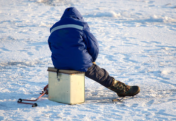 Fototapeta na wymiar A man on ice is fishing in the evening