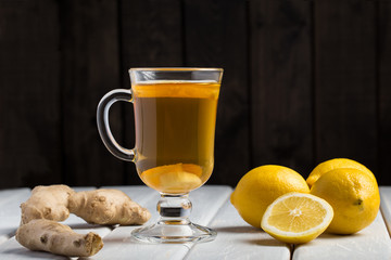 A cup of ginger tea with lemon on a wooden background.
