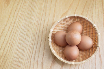 Eggs in a wooden basket on wooden floor background