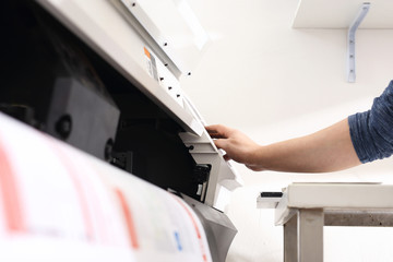 Praca w drukarni.Pracownik obsługuje maszynę drukującą.
