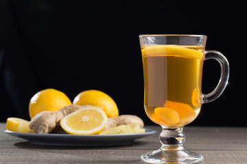 A cup of ginger tea with lemon on a wooden background.