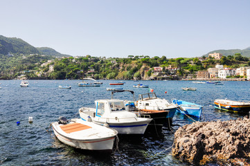 Fototapeta na wymiar Italian summer holidays in Ischia, blue sea and sky on a Sunny day, beaches and houses on the coast, many white yachts and boats