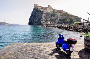 Italian summer holiday on Ischia island, blue sea, beach and castle on the rock, scooters...