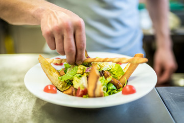 Close-up of chef's hands, preparation of salad in the kitchen, traditional Italian dishes