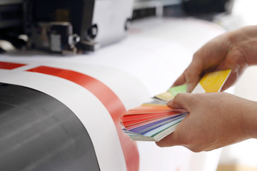 Maszyna drukarska, kolorowy wydruk. Drukarz sprawdza kolor wydruku na próbniku kolorów. - obrazy, fototapety, plakaty