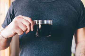 uomo che regge una tazza di caffè vicino a una finestra