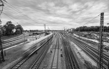 Obraz premium Bahnhof mit Gleisanlage in Augsburg und einem vorbeifahrenden Zug in schwarzweiss