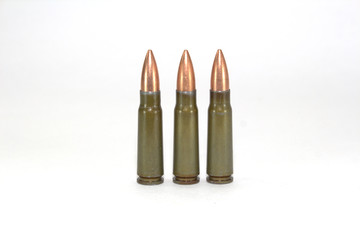 three cartridges for a Kalashnikov assault rifle on white background close-up