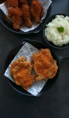 Spicy fried chicken set serving on black pan and white paper on dark table