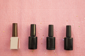 Obraz premium Black bottles of nail polish or gel isolted on pink background with copy space.