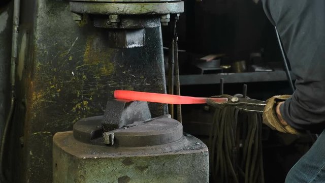 Using pneumatic hammer to shape hot metal. Making the sword out of metal.