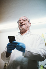  59  year  old man with smartphone and latex gloves