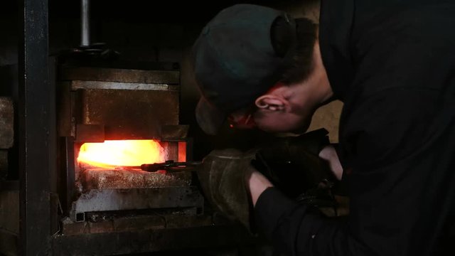 Making the sword out of metal at the forge. Blacksmith pulls out of the furnace hot metal blanks.