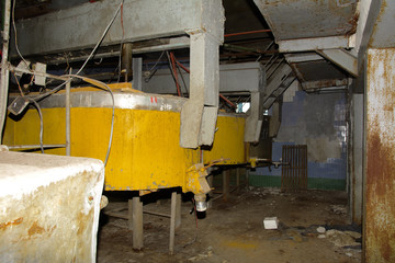 Fototapeta premium Old rusty and disassembled equipment for producing milk in an abandoned and destroyed factory amidst chaos. Destruction and vandalism. Ukraine.