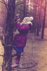Naklejka premium Cute little girl in pine forest in autumn time