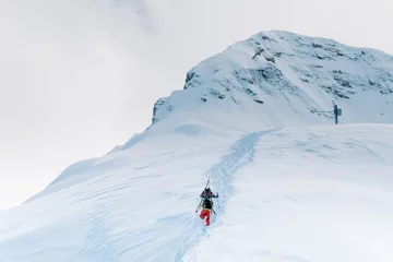 Cercles muraux Sports dhiver Two skiers in color suits climb a high mountain