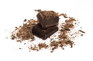piece of dark chocolate with shavings on white background