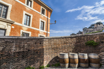 Barrels, walls and orange building in a street of Rome.