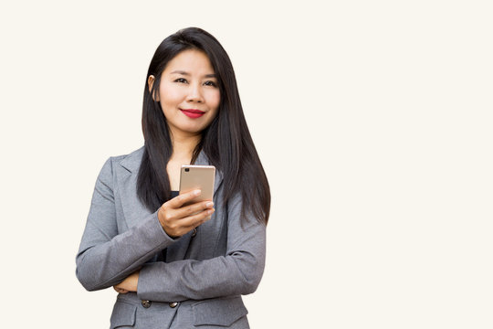 portrait of happy Asian business woman standing with smart phone in hand smiling at camera isolated on white background