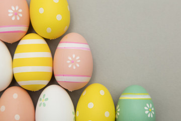 Easter holiday background. Pastel coloured decorated easter eggs on a grey background