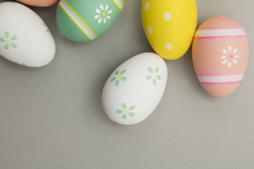 Easter holiday background. Pastel coloured decorated easter eggs on a grey background