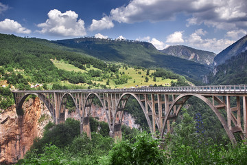 Fototapeta na wymiar Old big bridge in Durdevica and fantastic view Tara river gorge - is the biggest one canyon in Europe in the national park Durmitor, Montenegro. Balkans.