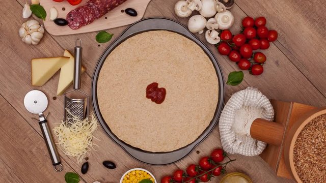 Top view of making a pizza with ingredients appearing on the slowly rotating setting - stop motion animation, camera rotates