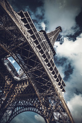 Low-angle view of Eiffel Tower against cloudy sky
