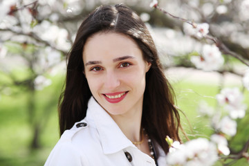 Fototapeta premium Portrait of a young woman against a background of blossoming apricot