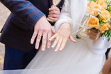 Wedding golden rings on the fingers of the bride and groom. Closeup.