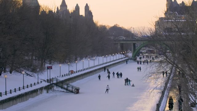 Tilt up of People Skating on the Rideau Canal in Winter and View of Downtown Ottawa