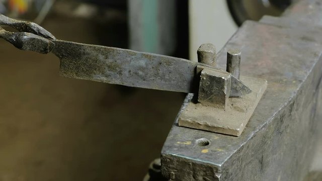 Making the knife out of metal at the forge. Alignment of the knife blades after hardening of the metal.