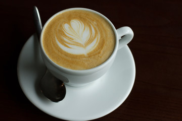 cappuccino in white cup with spoon on black table