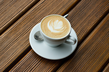cappuccino in white cup with spoon on wooden table