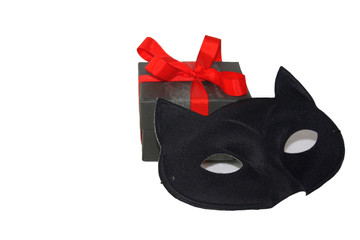 Little cute gift box with bright red ribbon and mysterious eye cat mask, isolated on white background.