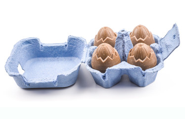 Packed four chocolate eggs in a blue box isolated on white background.