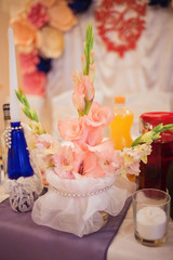 Wedding table decoration, peach blossom gladiolus flowers in a vase decorated with silver beads.