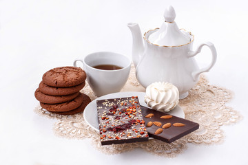 white still life with a Cup of black tea, black fruit chocolate and biscuits