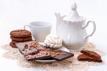 white still life with a Cup of black tea, black fruit chocolate and biscuits