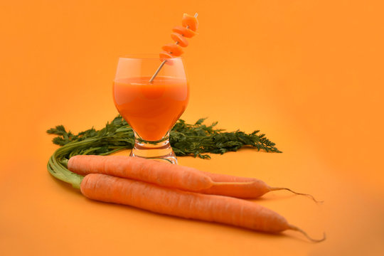 Carrot juice stock images. Glass of carrot juice with oranges. Carrot on orange background