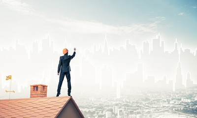 Man architect draw silhouette of modern city on blue sky. Mixed 